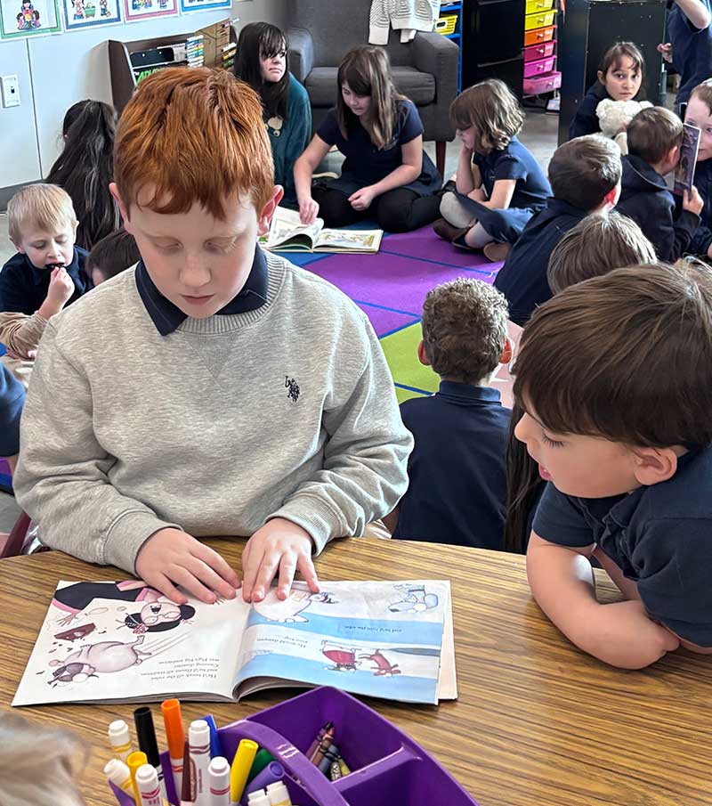 Third grade student reads to another student.