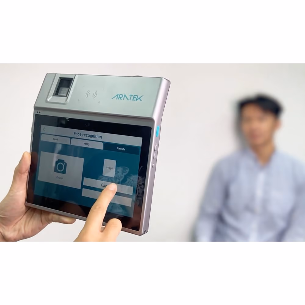 A man's hand held Aratek Marshall 8 biometric tablet to check a man's identity with his face biometrics