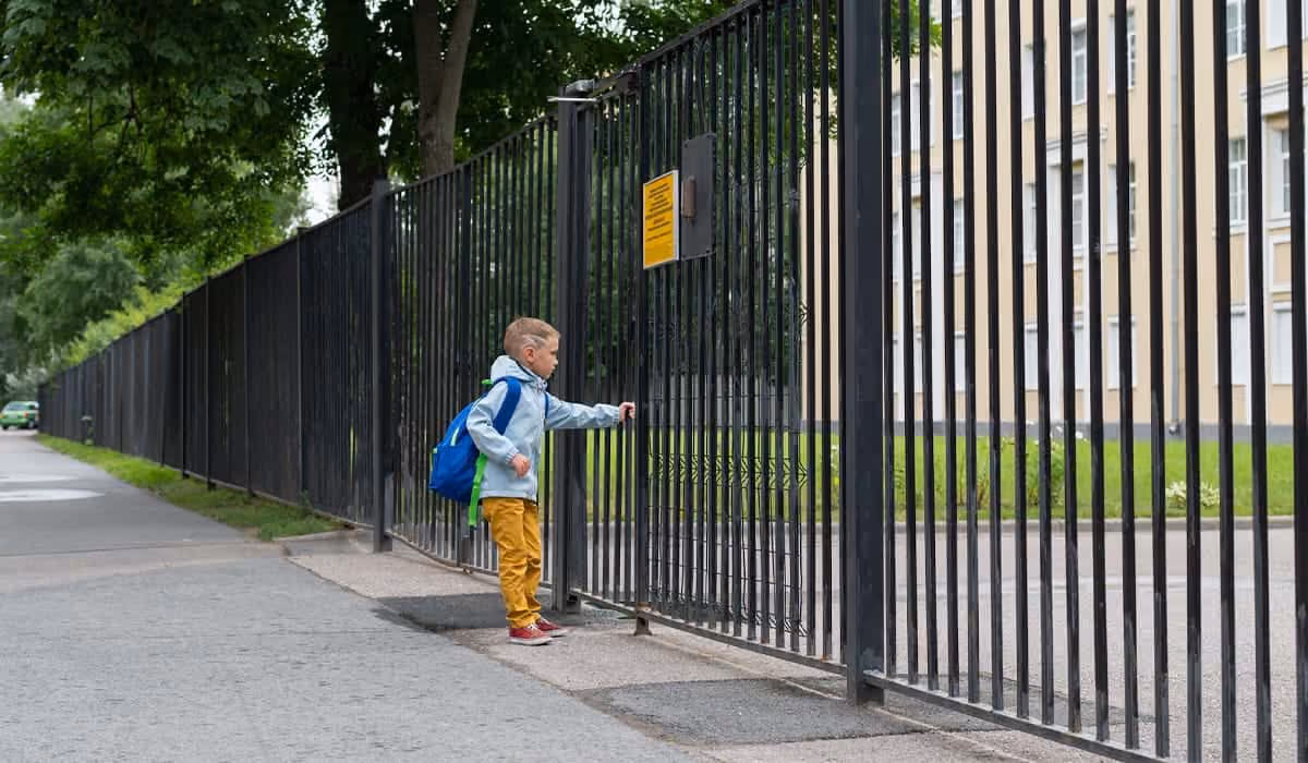 A boy want to open a school gate physical barrier