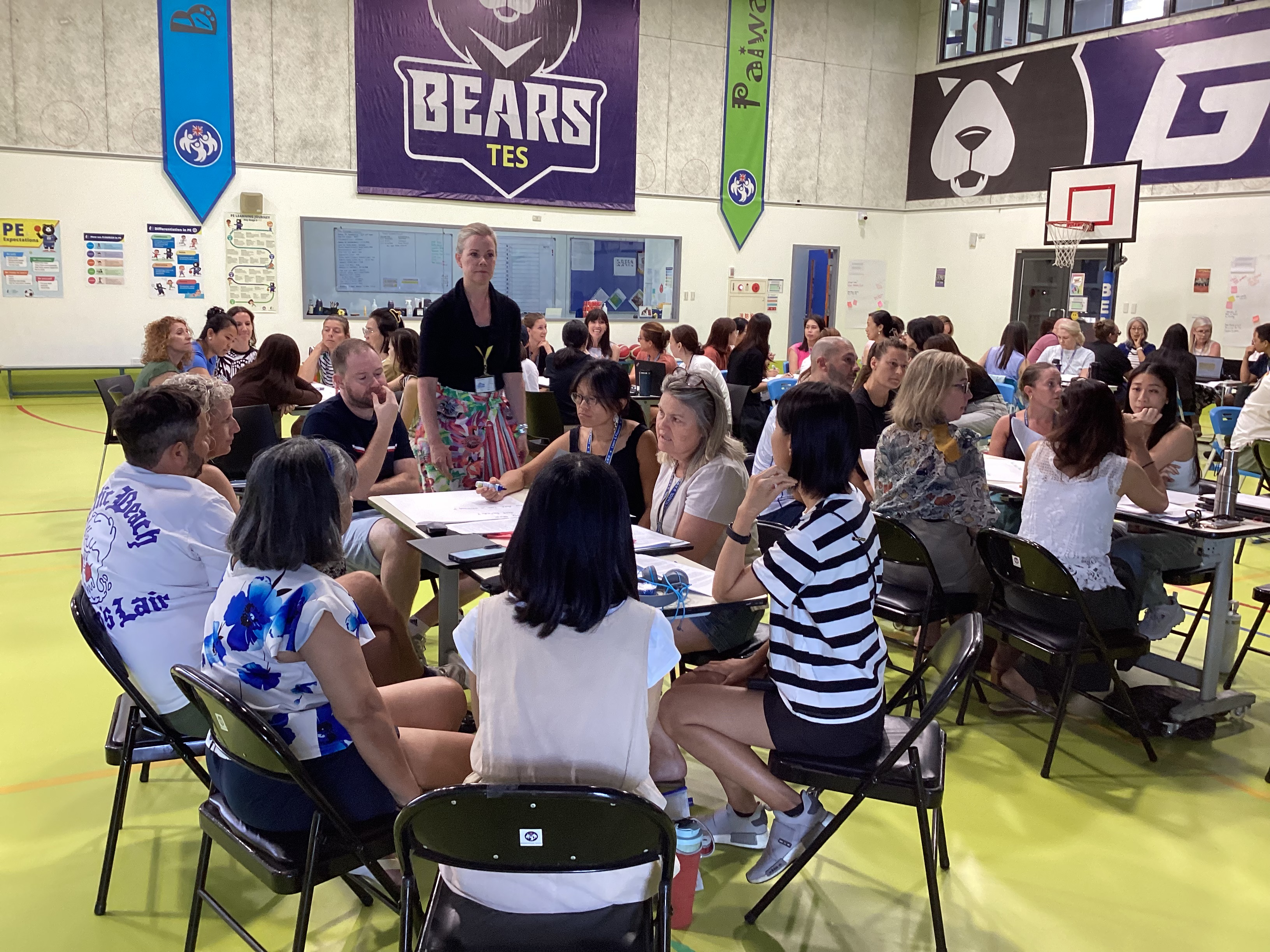 Group meeting in school gymnasium with Bears team banners