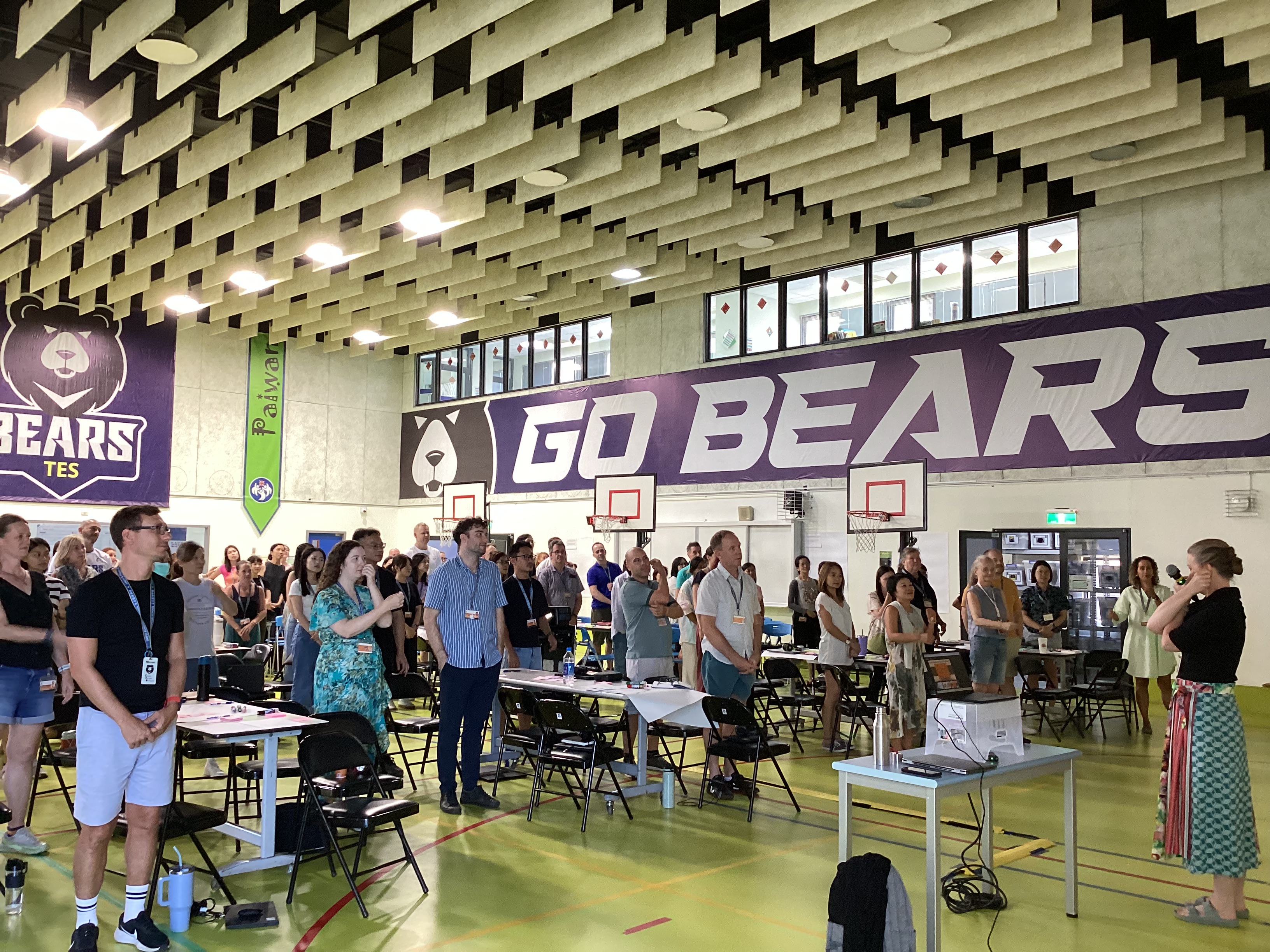 Large group gathered in school gymnasium with "Go Bears" banner