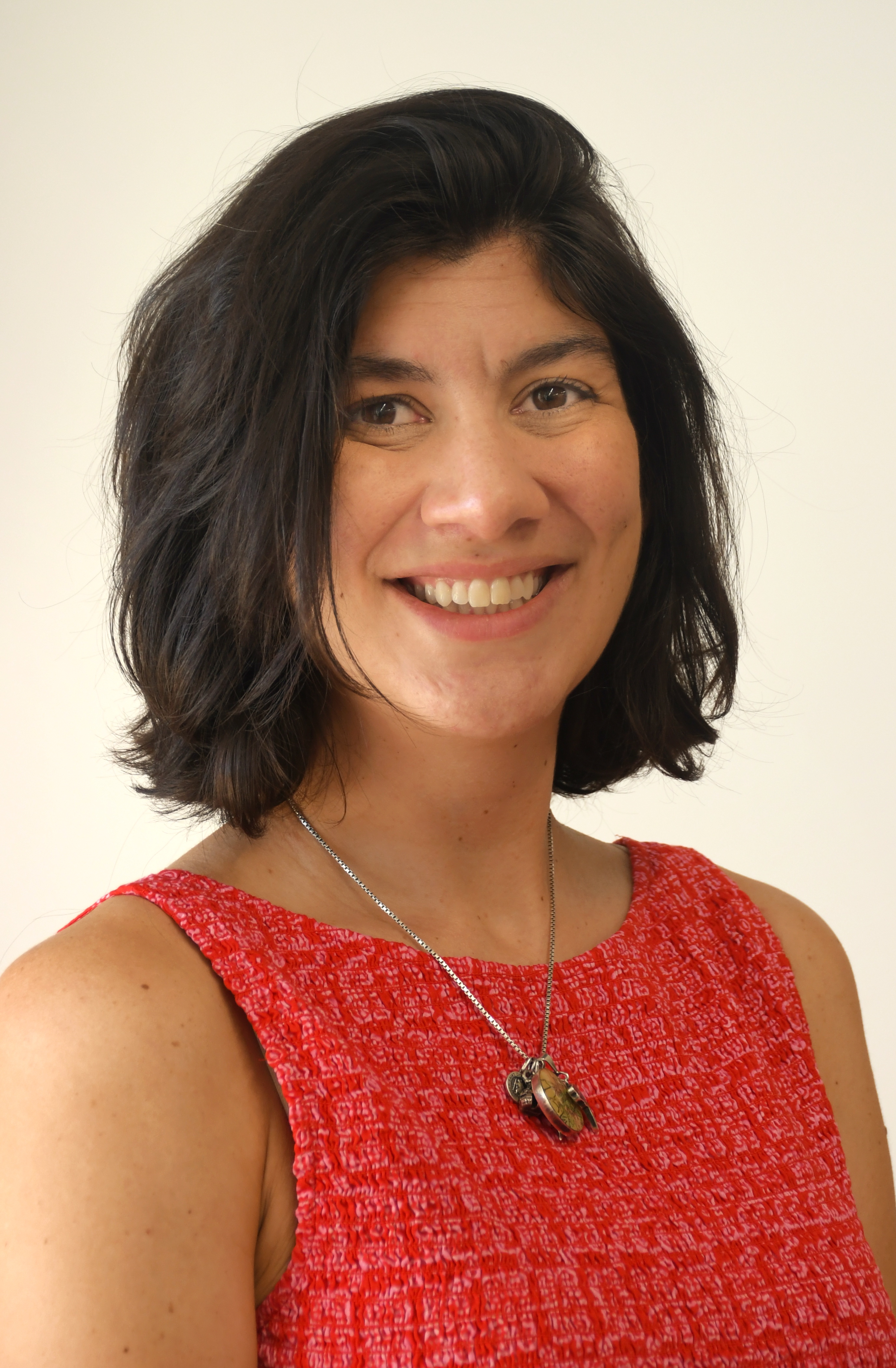 Smiling woman in red dress with short black hair and necklace