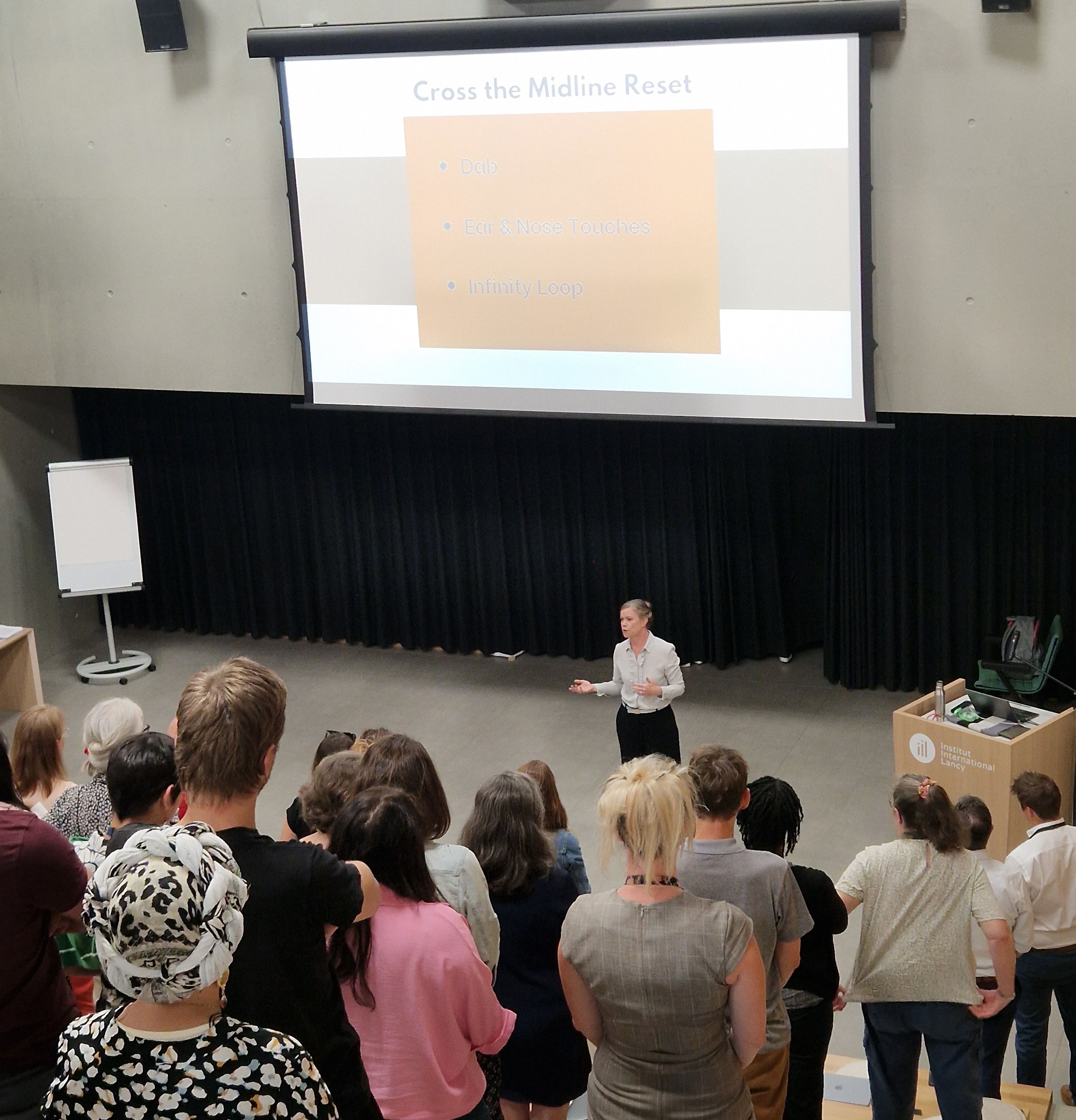 Presenter giving a talk about "Cross the Midline Reset" to an audience
