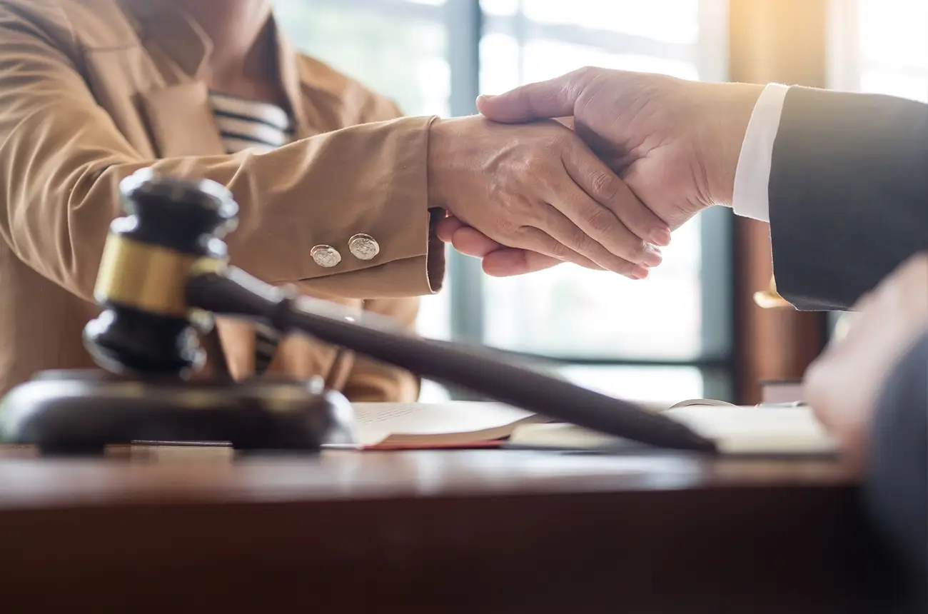 An employment lawyer and client shake hands after meeting about a discrimination claim.