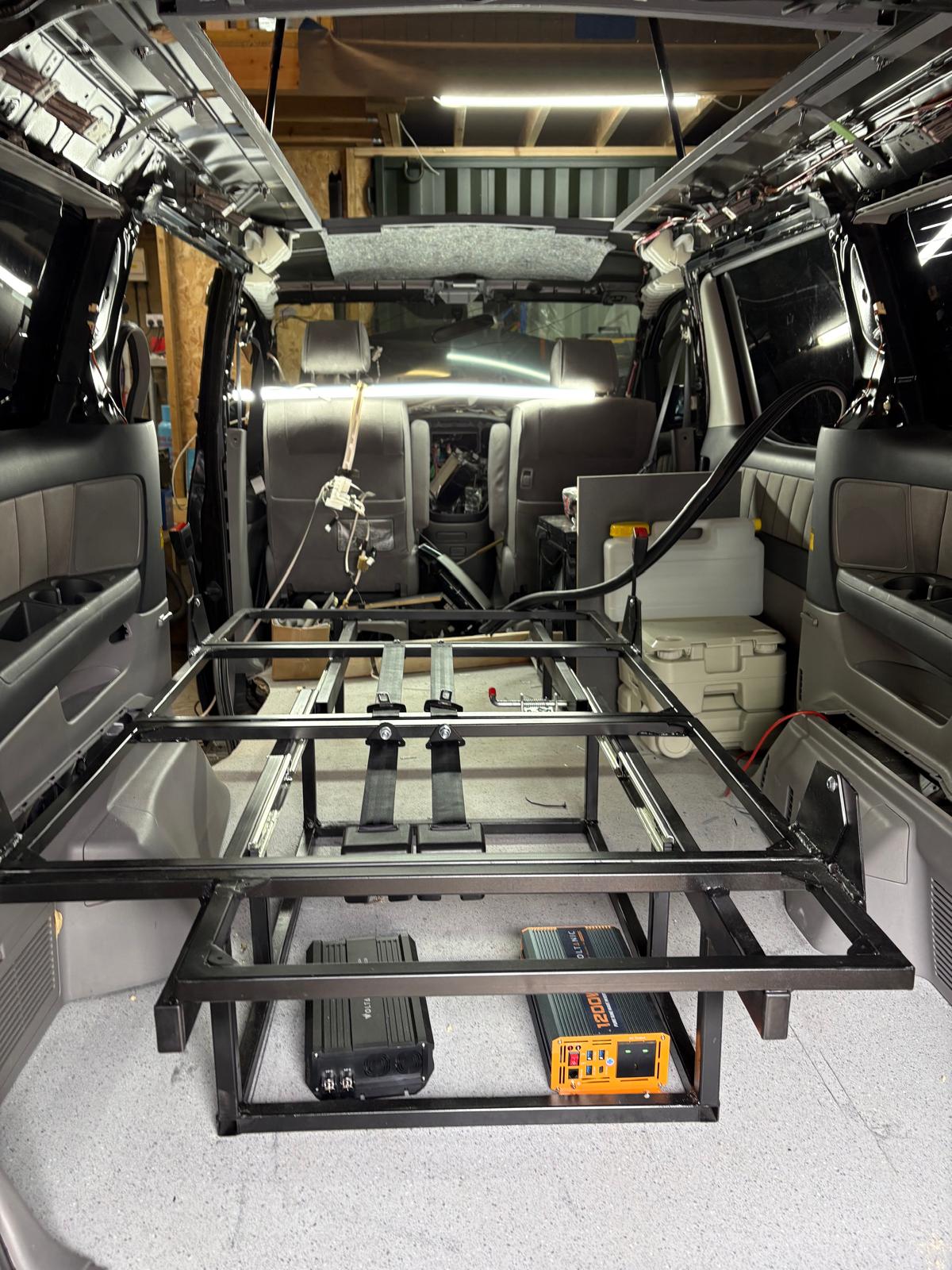 Metal frame structure installed inside a vehicle with electrical devices and seats visible.