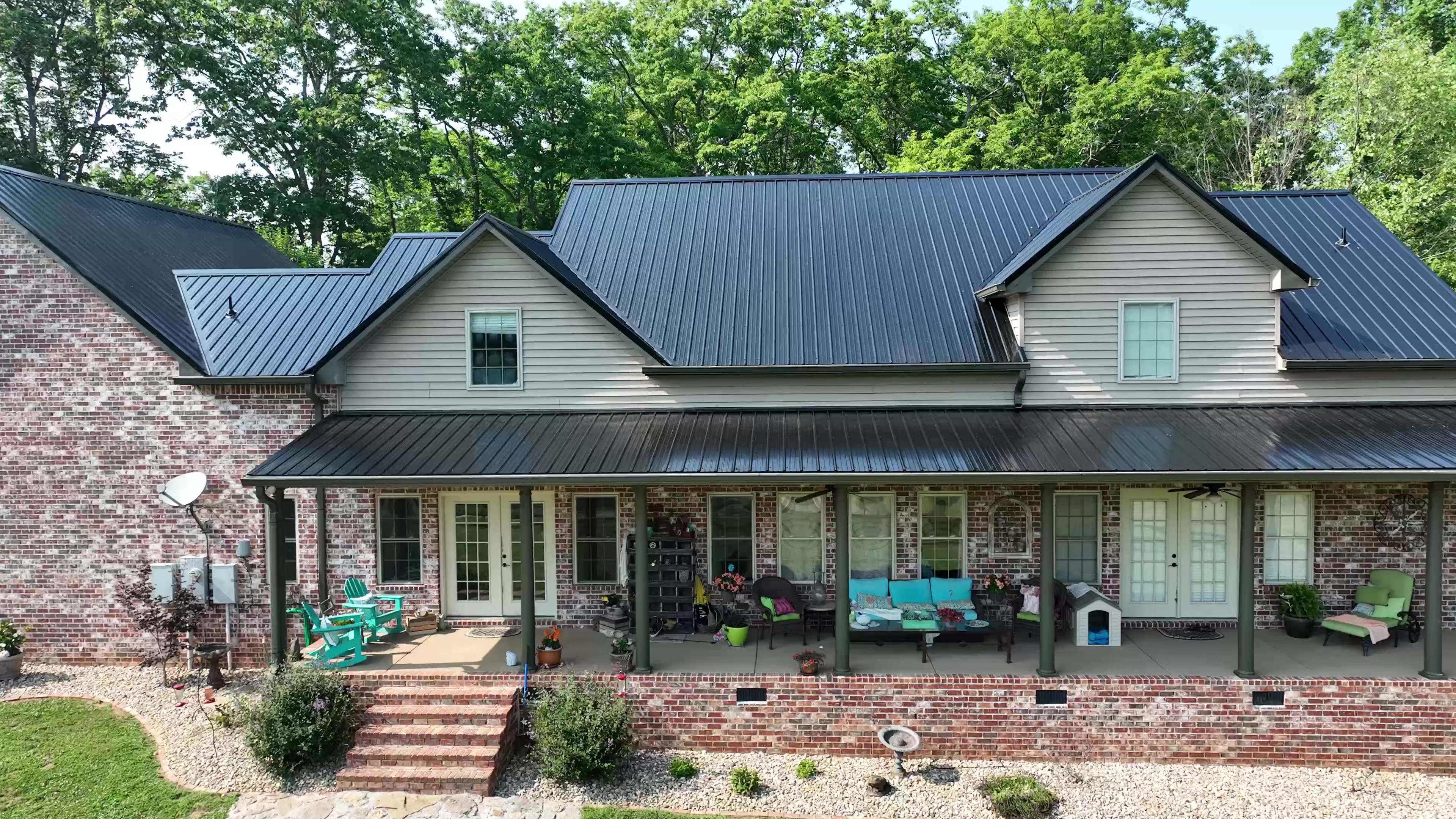 Wraparound Porch Farmhouse with a Black Classic-Panel Metal Roof