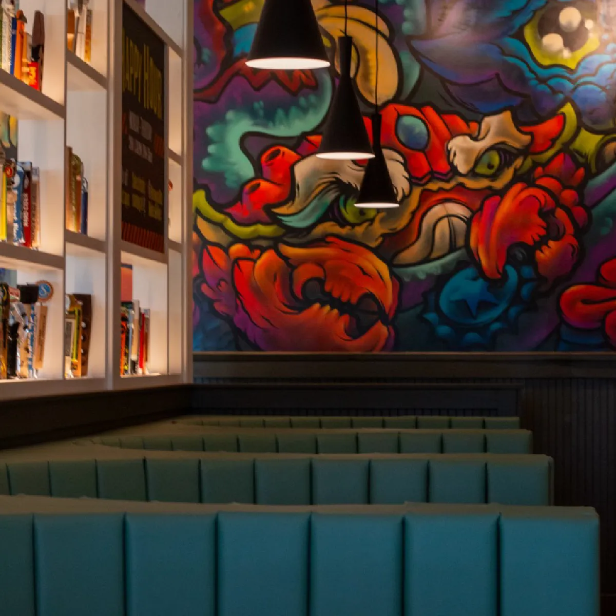 HopCat southgate restaurant seating with teal booths under pendant lights and a colorful abstract mural on the wall.