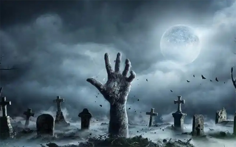 Hand reaching out of the ground in a graveyard