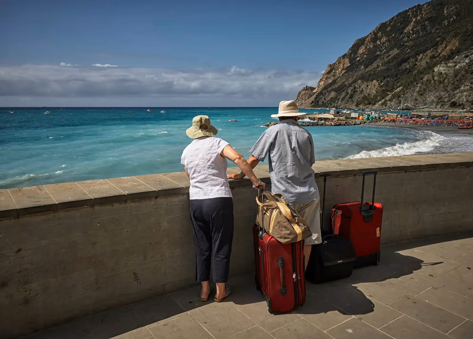 Man and woman looking at the beach with their luggages