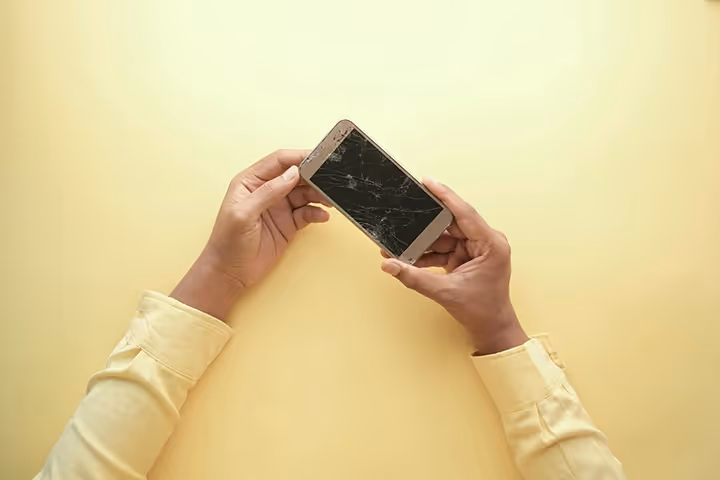 Man holding broken mobile phone
