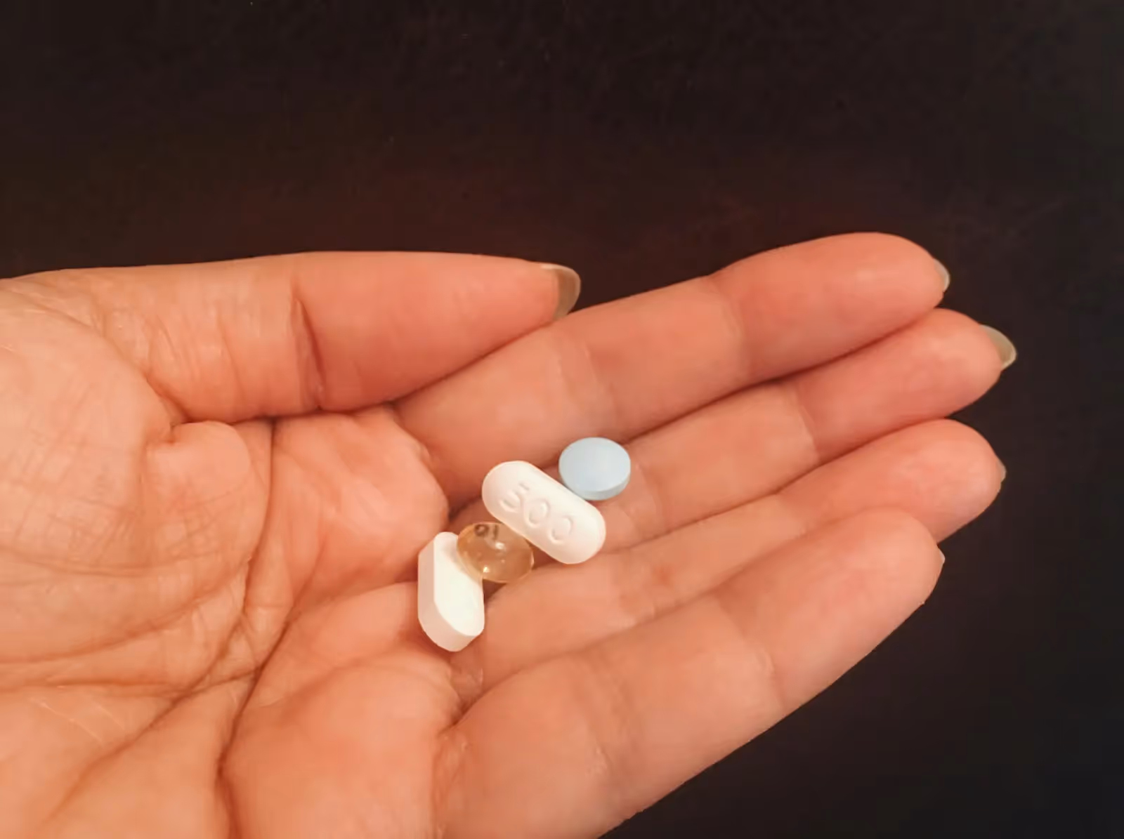 Person holding four kinds of tablets
