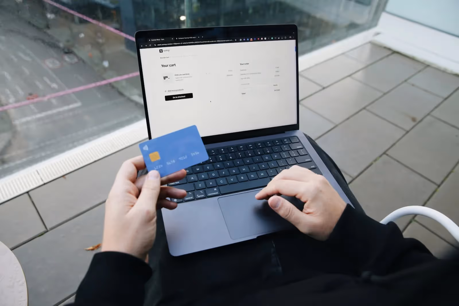 Person using a laptop while holding a credit card