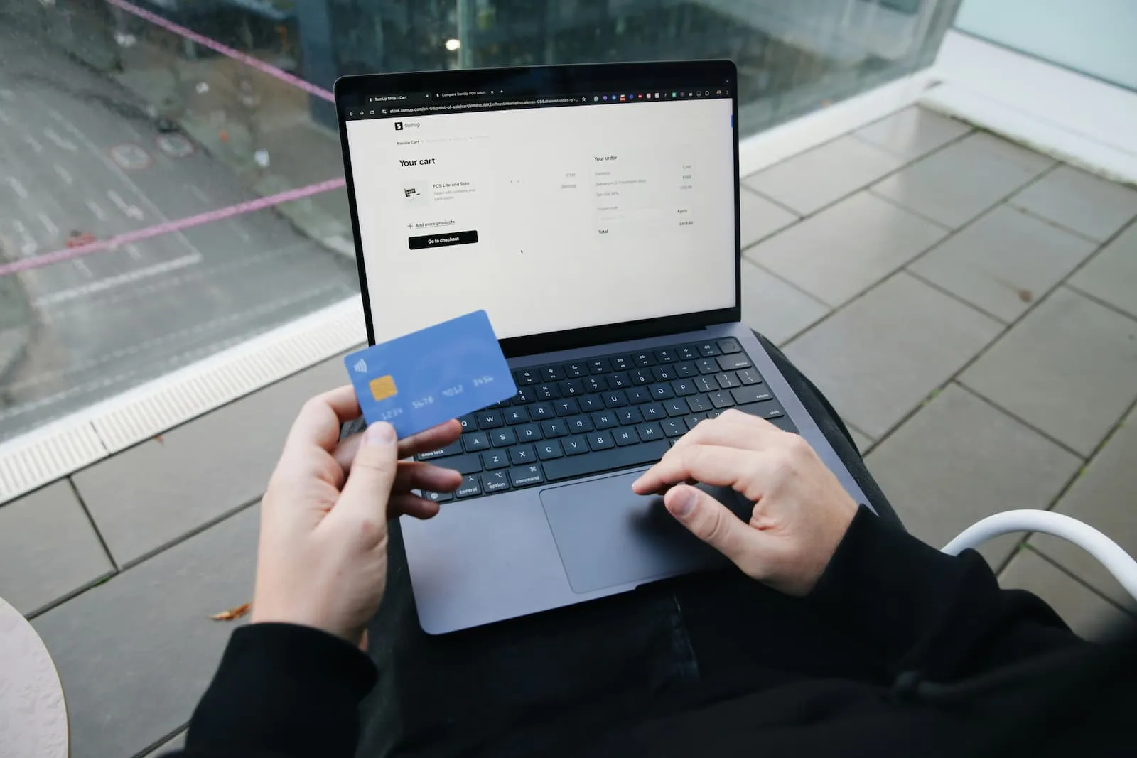 Person using a laptop while holding a credit card