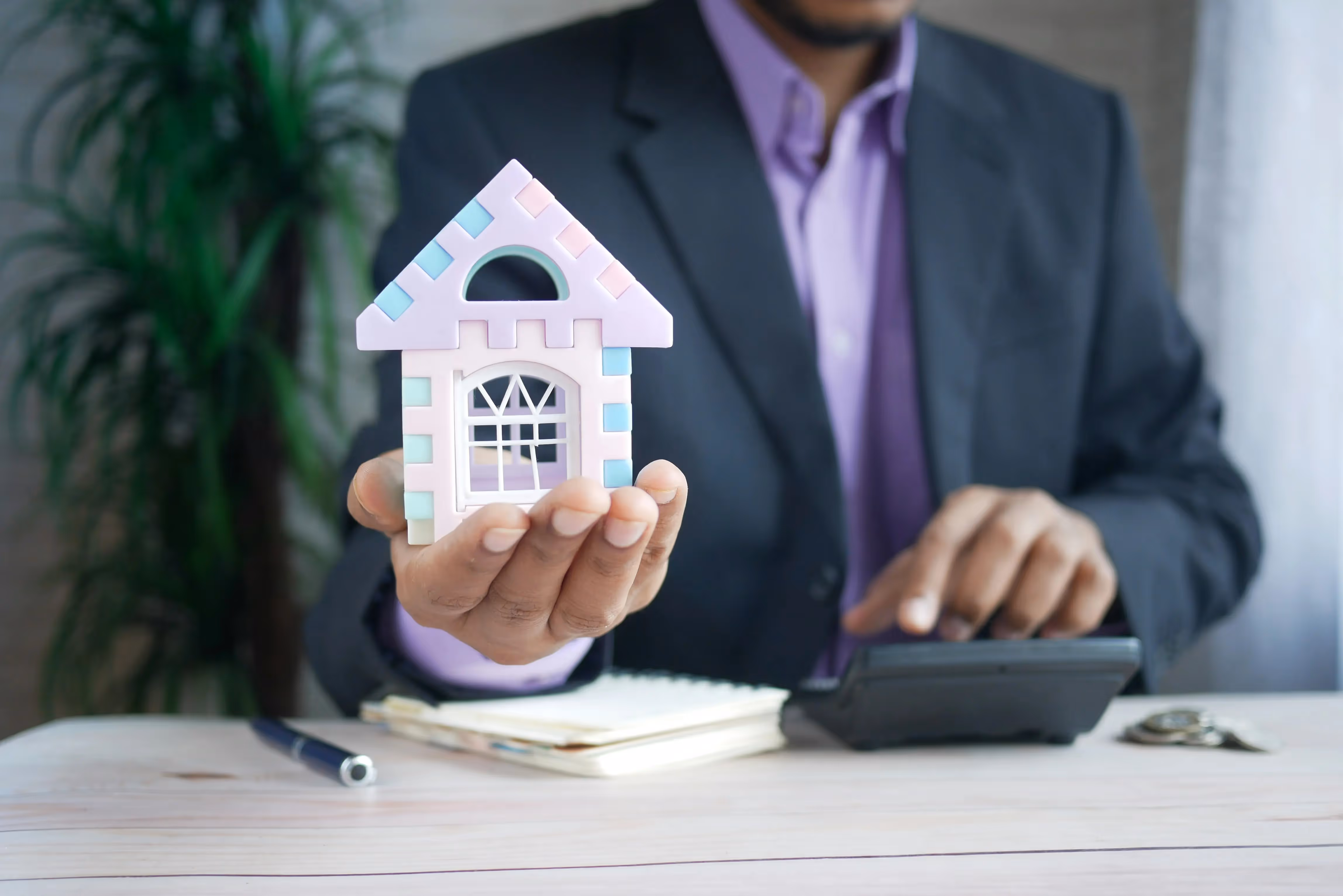 Person in a suit holding a miniature house