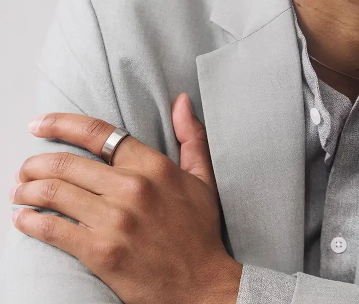 A man displays a silver Oura ring on his left hand, highlighting its shine and design