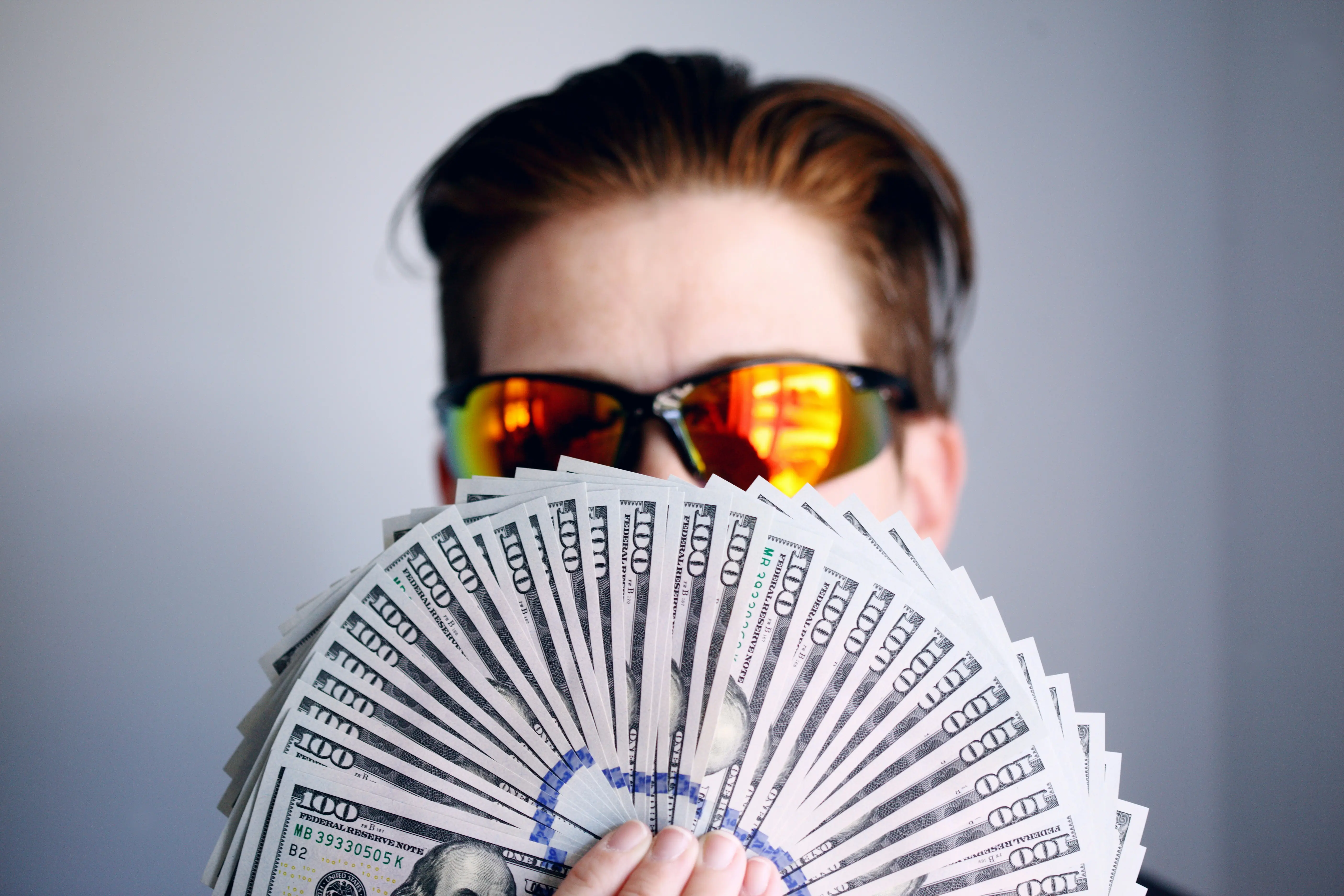 Person wearing sunglasses holding money