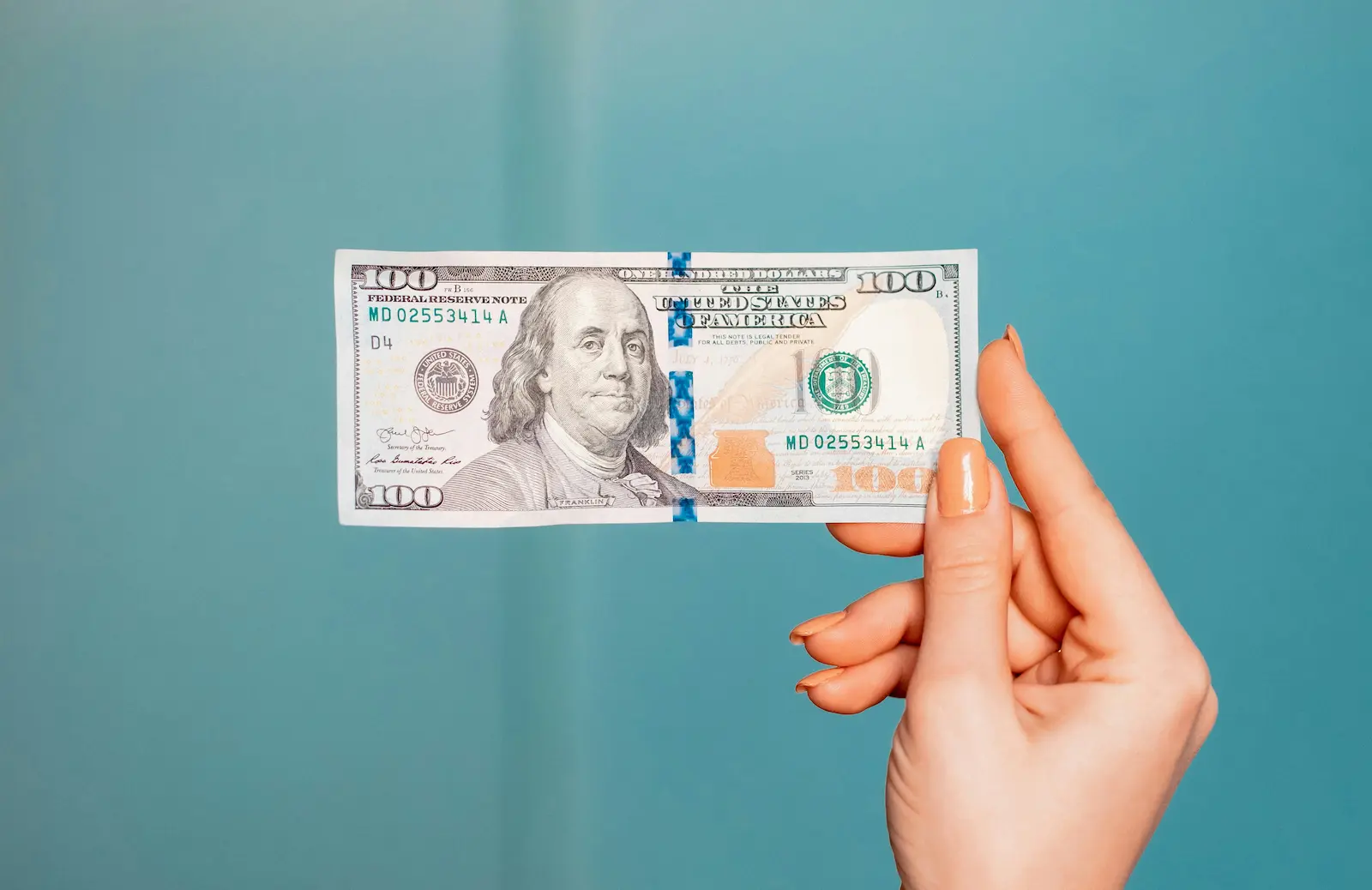 Person holding a one hundred dollar bill