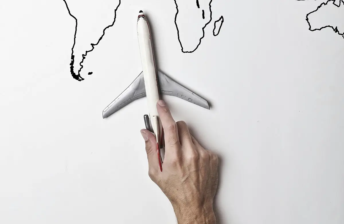 Man holding airplane in front of world map