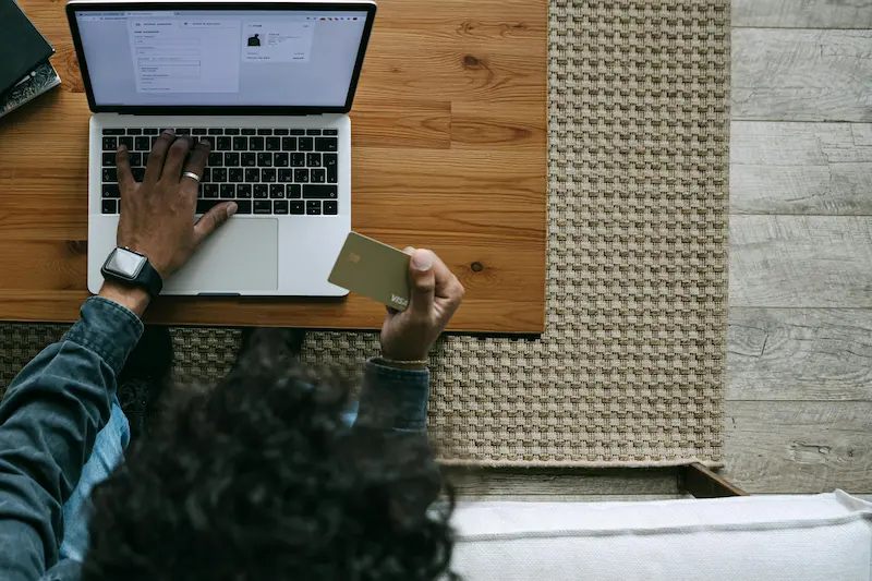 Person filling out a credit card application on a laptop with a credit score report nearby