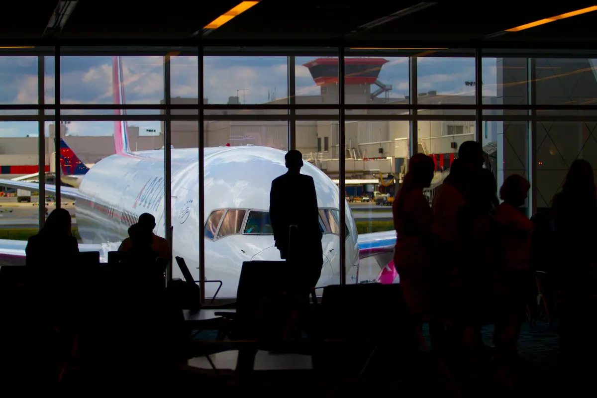 Person holding a travel rewards credit card at an airport departure gate ready to fly