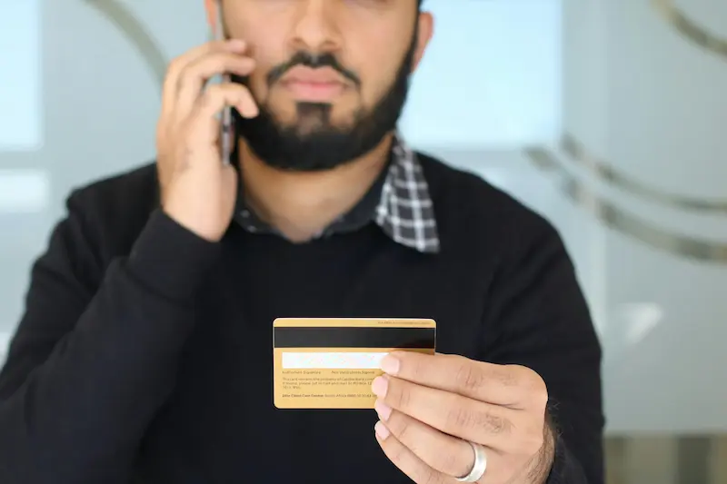 Person holding a credit card while on a phone call — step-by-step guide to asking for a credit card retention offer in 2026