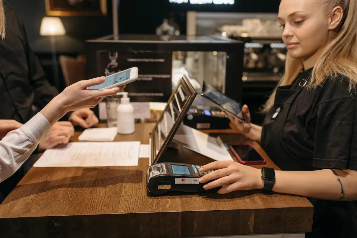 Person attempting to use Apple Pay at a cannabis dispensary checkout counter in 2026
