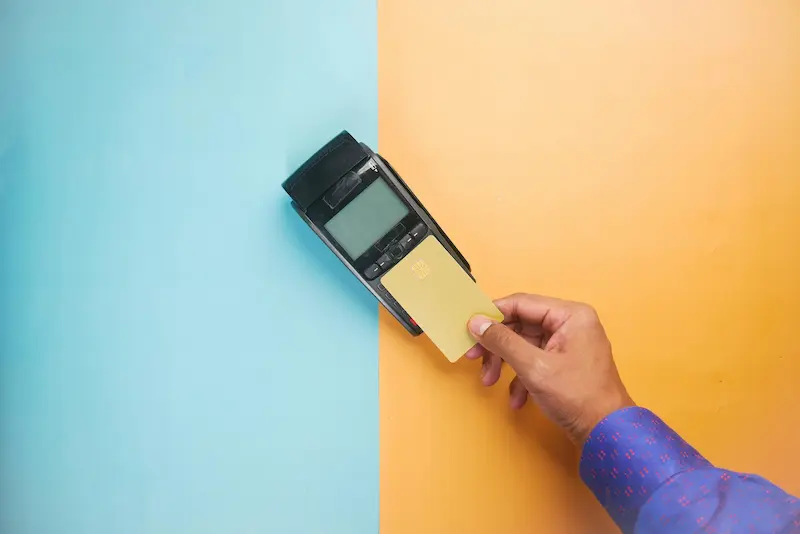 Person using a physical credit card at a retail store payment terminal in 2026