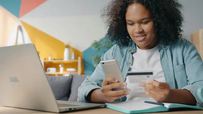 Person reviewing their credit score on a smartphone, representing the Fetch American Express Card's role as an unsecured credit-building option for applicants with fair credit in 2026
