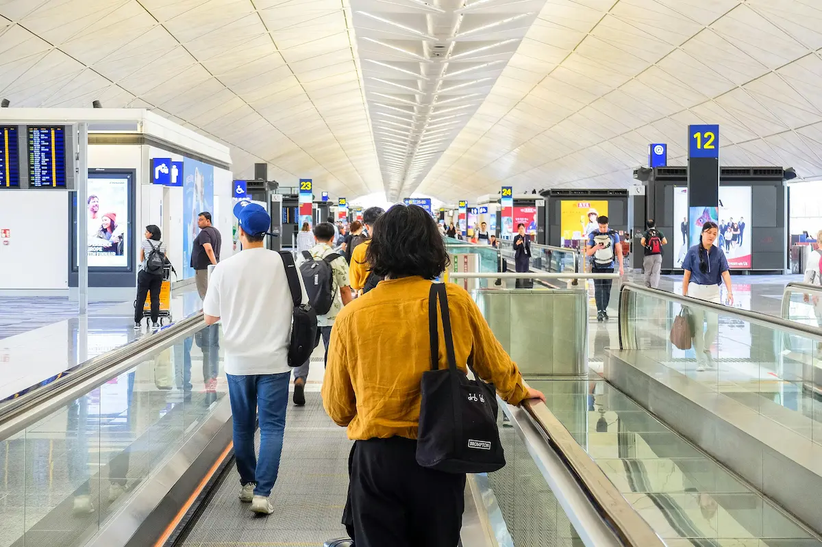 Traveler checking phone near airport lounge entrance to join digital waitlist