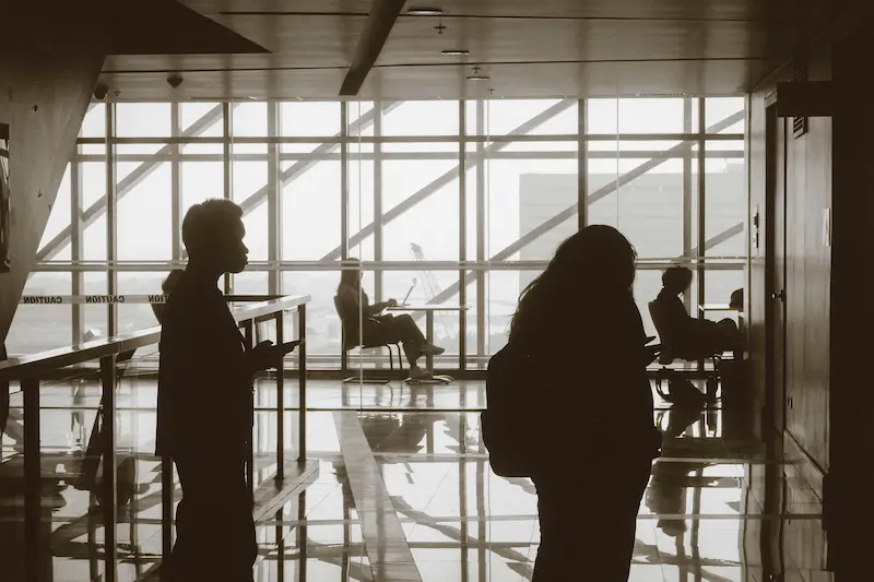 Traveler checking Priority Pass app at JFK airport gate to verify lounge access before clearing security in 2026