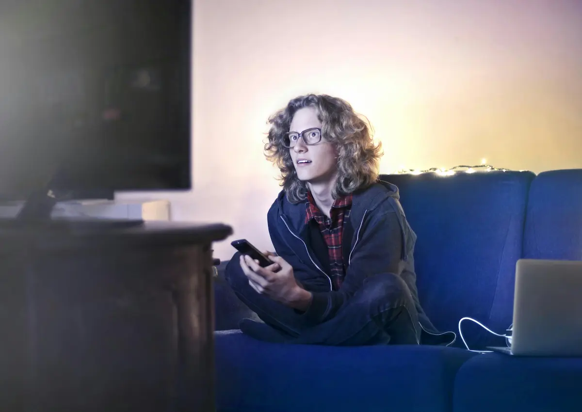 Person relaxing on a couch watching a streaming service in 2026, representing how to earn credit card rewards on Netflix, Hulu, Disney Plus, and more.