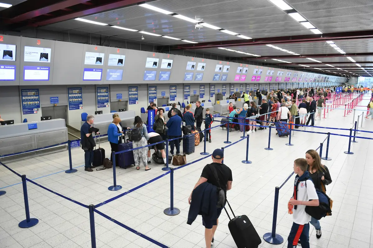 Travelers waiting in line at airport check-in counters, illustrating the airport wait times TSA PreCheck helps veterans avoid