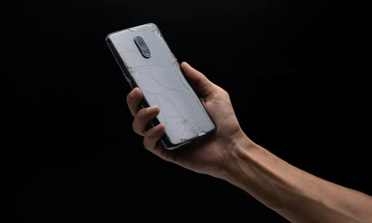 Hands holding a shattered phone