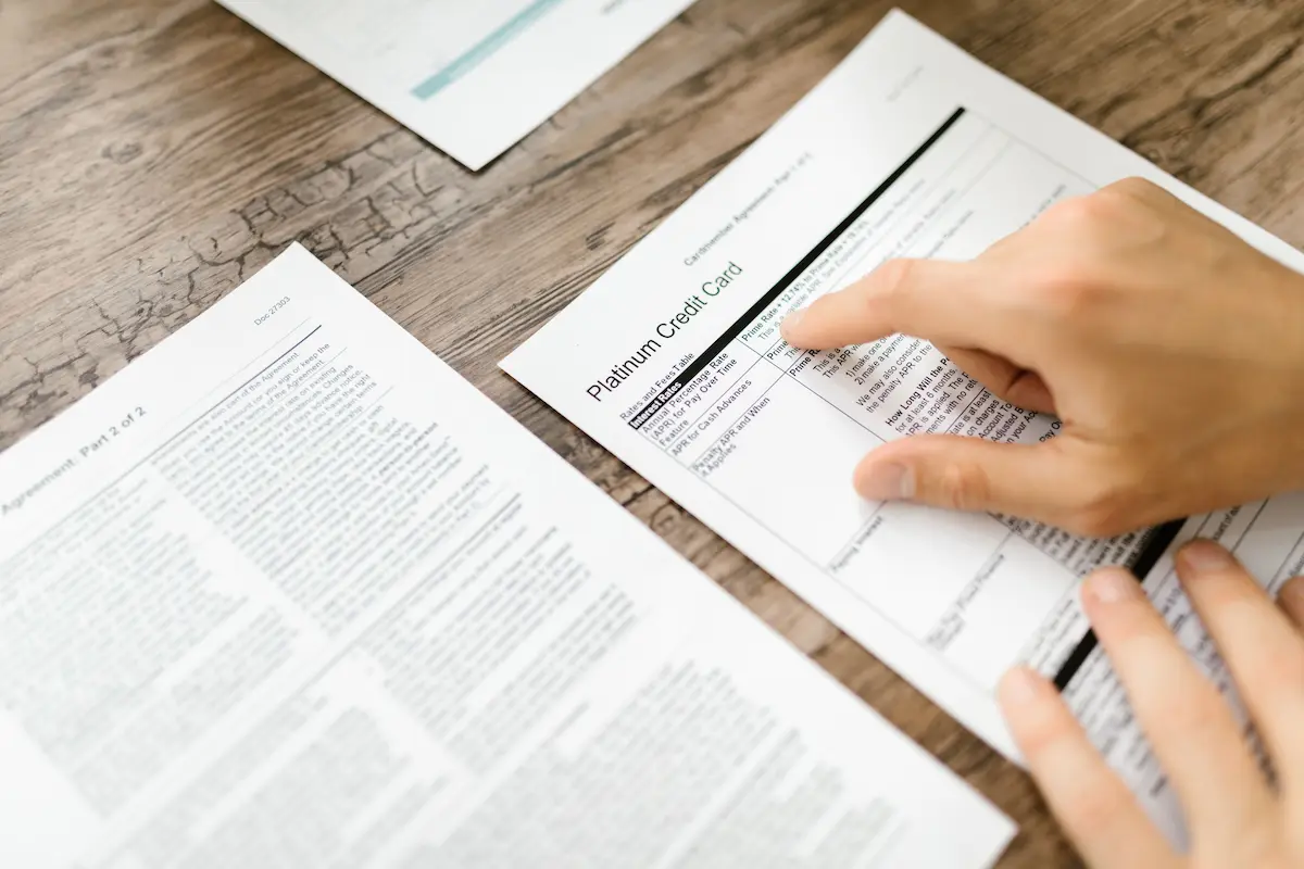 Close-up of a hand reviewing a credit card's rates and fees agreement document."