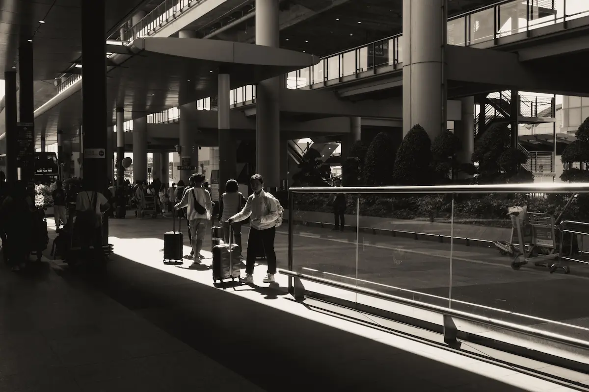 Travelers with luggage walking through an airport terminal.
