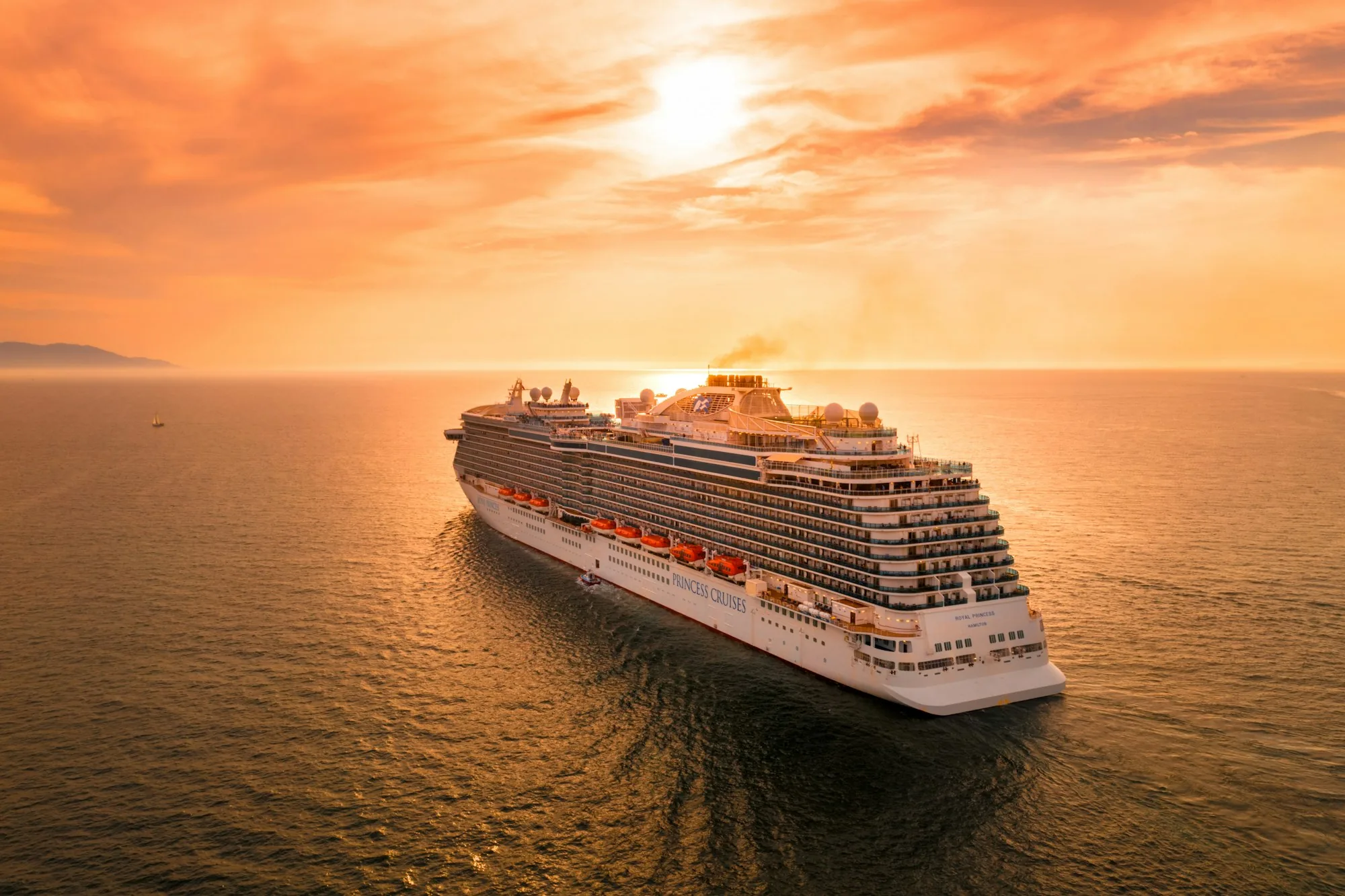 Cruise ship sailing on open water at sunset