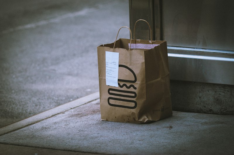 Brown paper takeout bag left at a doorstep, illustrating the Amazon Prime Grubhub promo code deal