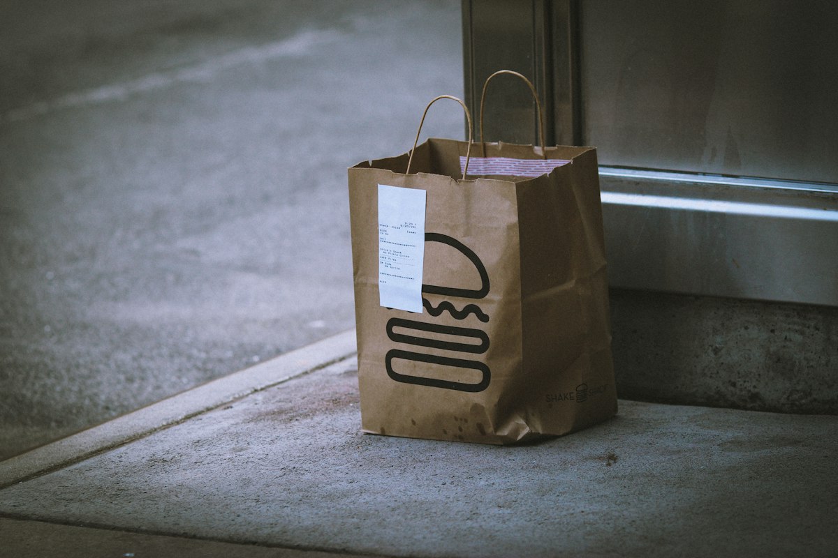 Brown paper takeout bag left at a doorstep, illustrating the Amazon Prime Grubhub promo code deal