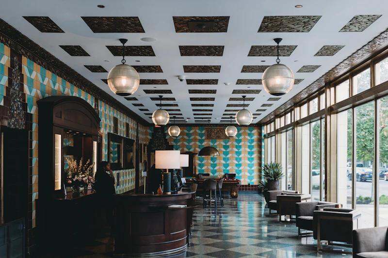 A hotel lobby with a checkered floor, pendant lights and lounge chairs