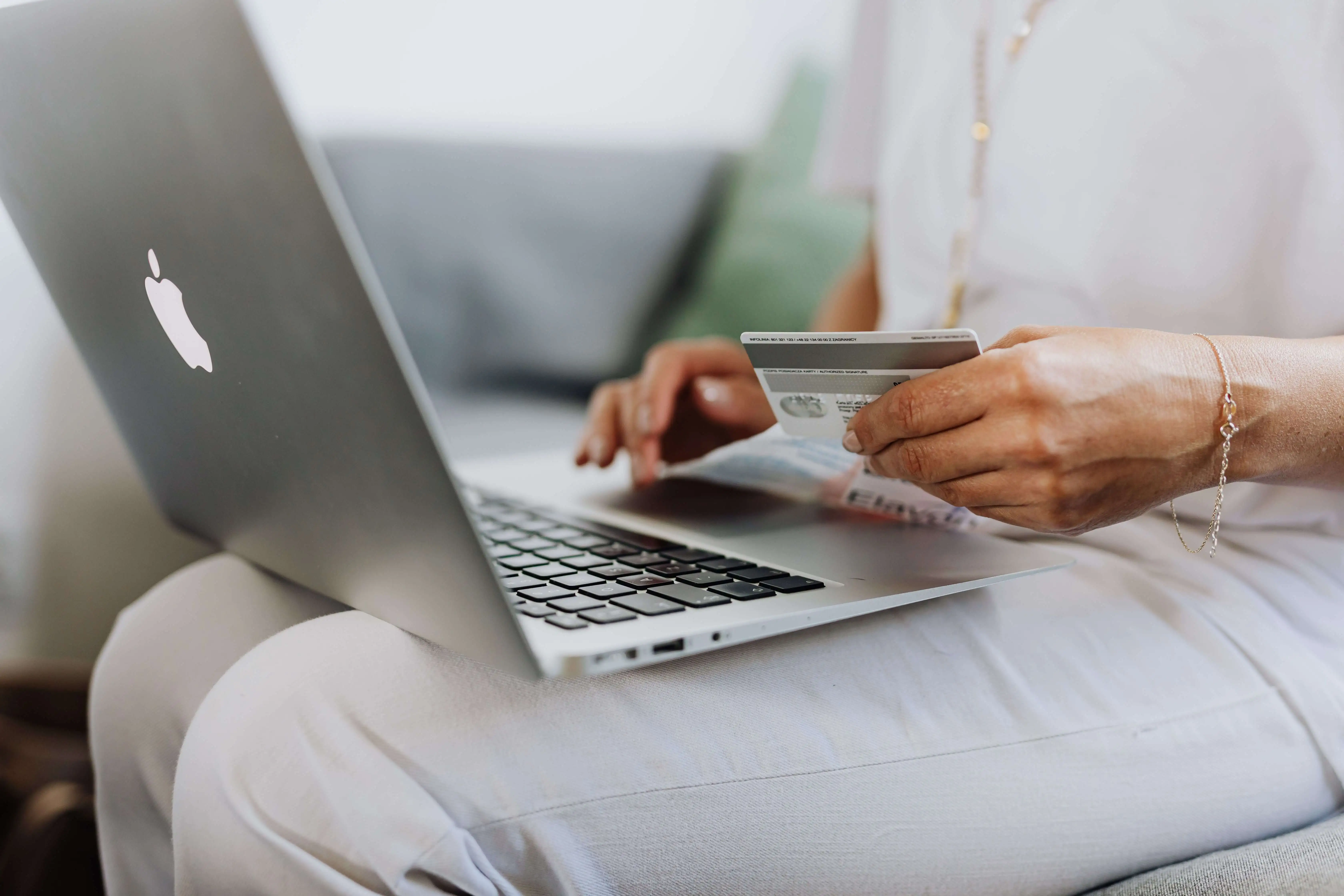 Person holding a credit card while shopping online on a laptop, deciding whether to pay with points at checkout
