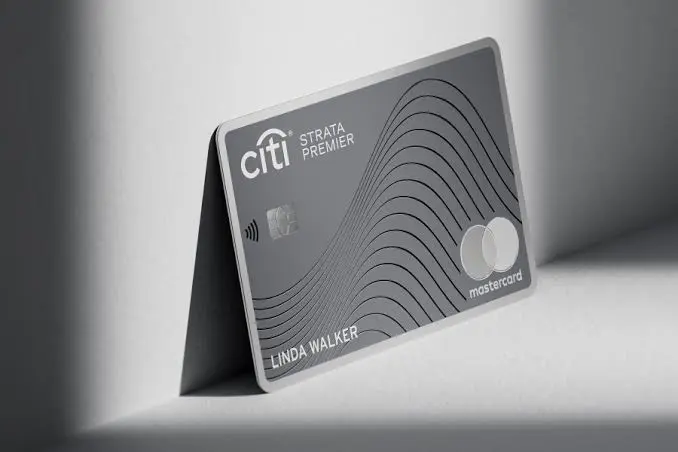 Citi Strata Premier® Card in metallic gray with a wave line design, standing upright on a white surface in soft shadow.