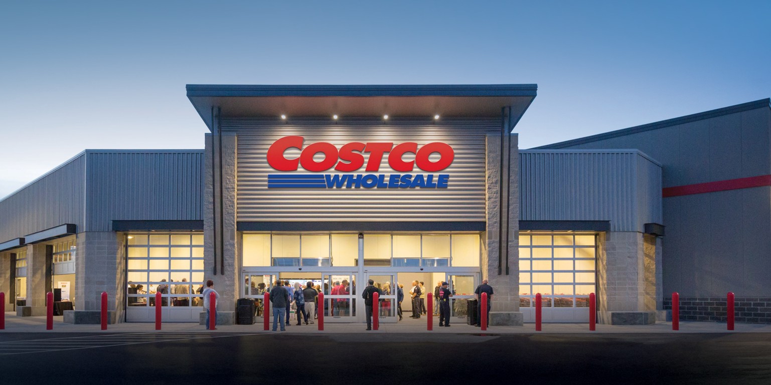 Shoppers at the entrance of a Costco Wholesale warehouse at dusk