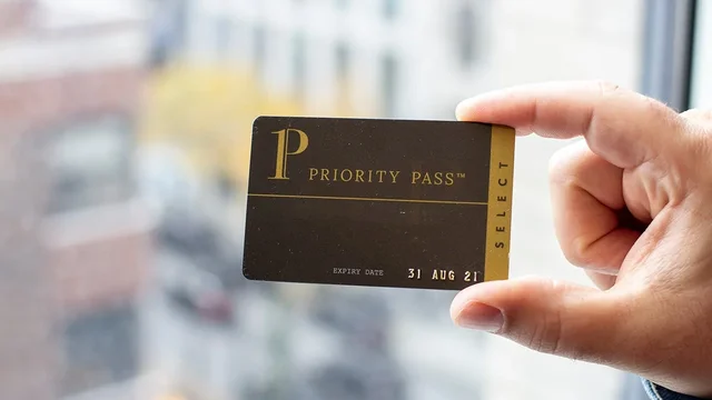 A Priority Pass Select membership card held up near a window