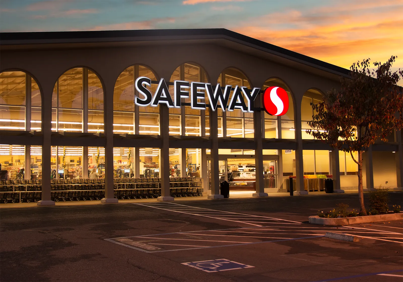 A Safeway grocery store storefront lit up at sunset