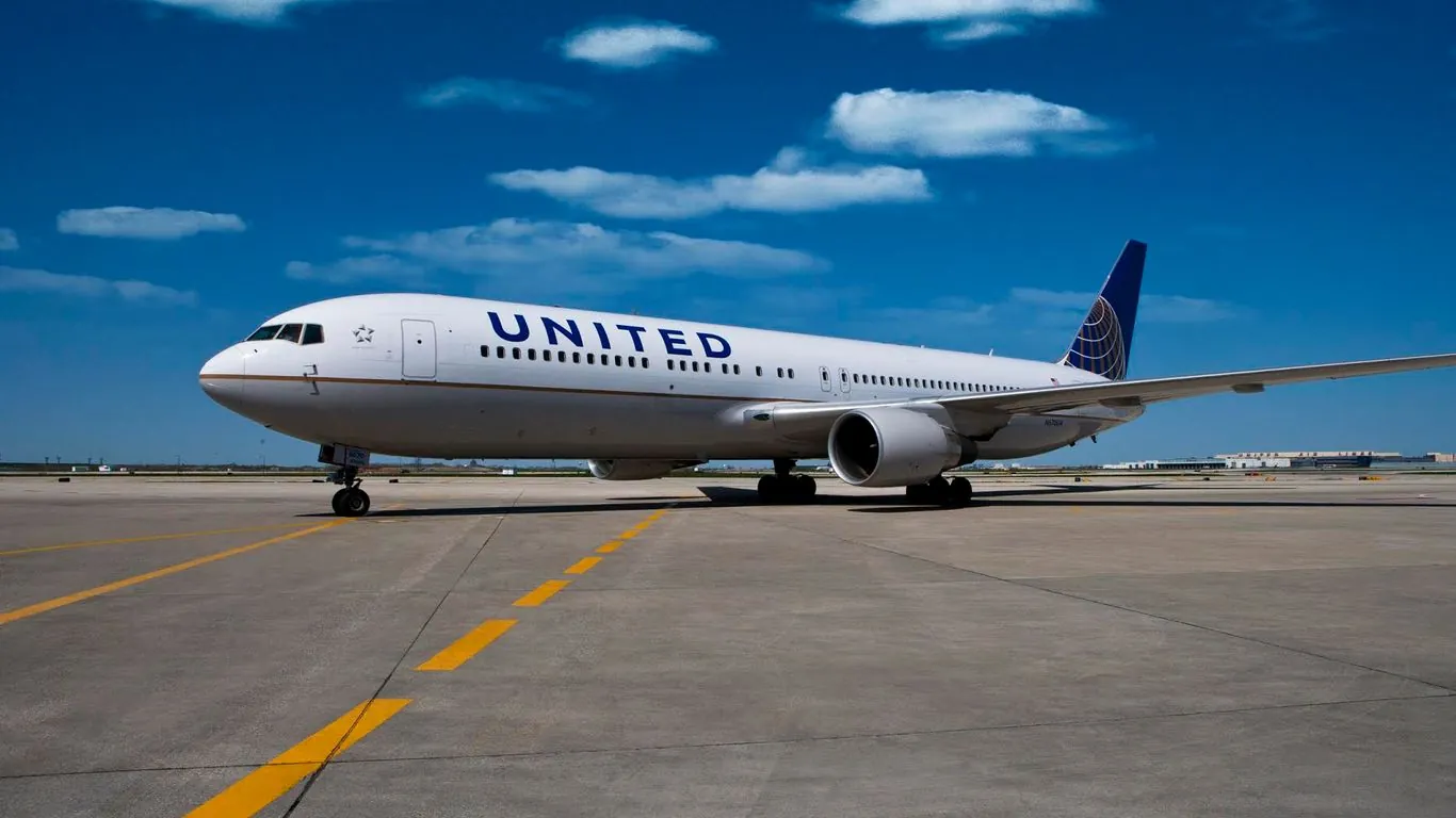 United Airlines plane parked on an airport tarmac under a blue sky