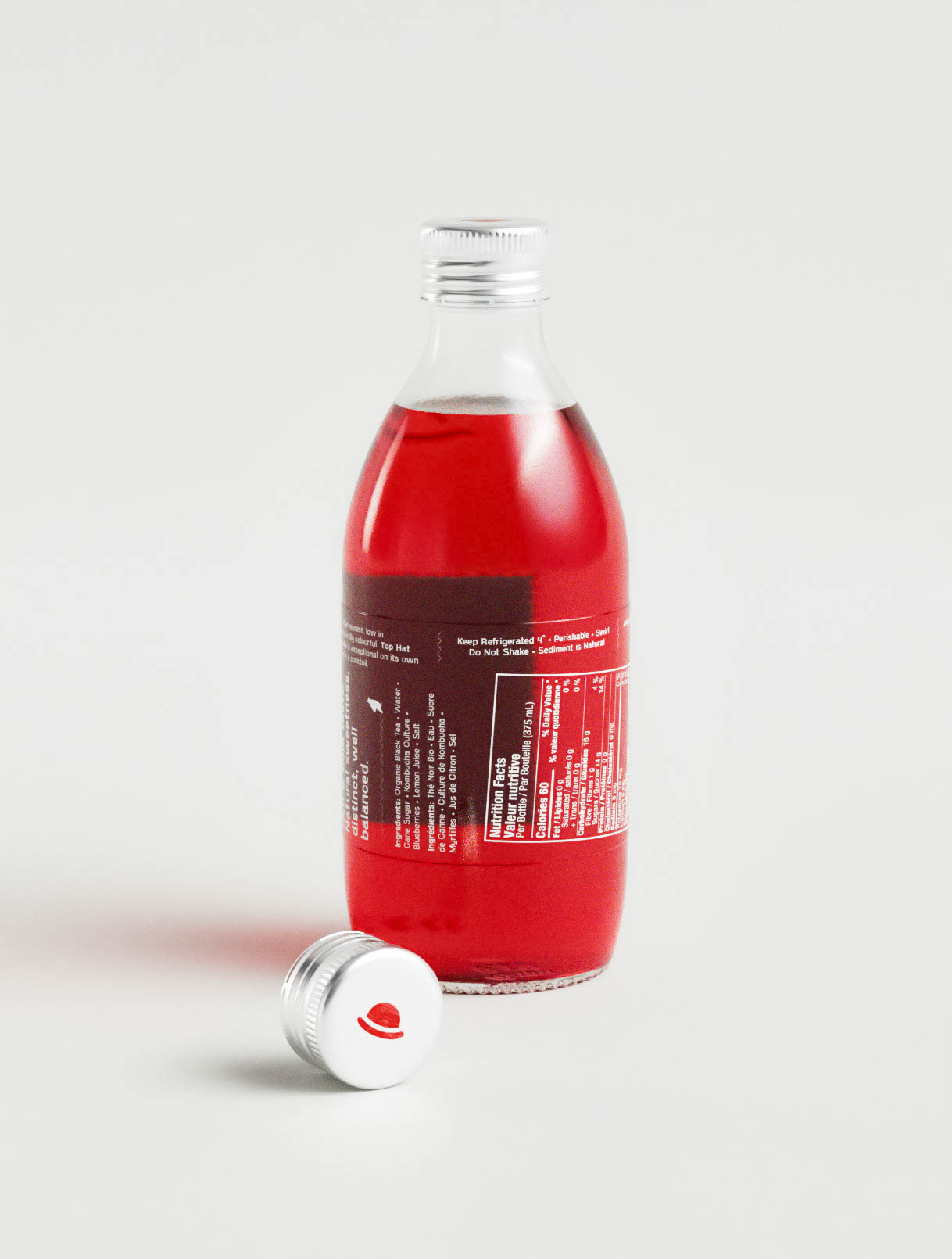 This final angle shows the bottle’s wraparound information panel in white type over a deep red kombucha base. Ingredients, usage instructions, and product claims are printed clearly in a dense but readable format. The symmetrical layout and cohesive typography choices reflect a considered approach to graphic design and creative direction. The glass bottle’s form remains visible behind the label, maintaining transparency and reinforcing the natural positioning of the brand. The bottle cap with its stylized red logo is positioned in the foreground, tying the composition together with subtle brand cohesion.