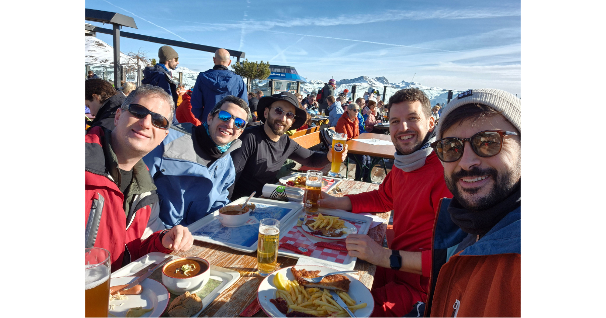 Anchor employees sitting at an outdoor table with food and a stunning view of the Alps in the background. 