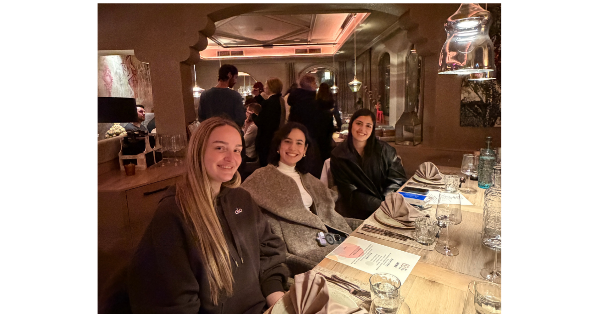Teammates sitting together at a dinner table ahead of a group meal. 