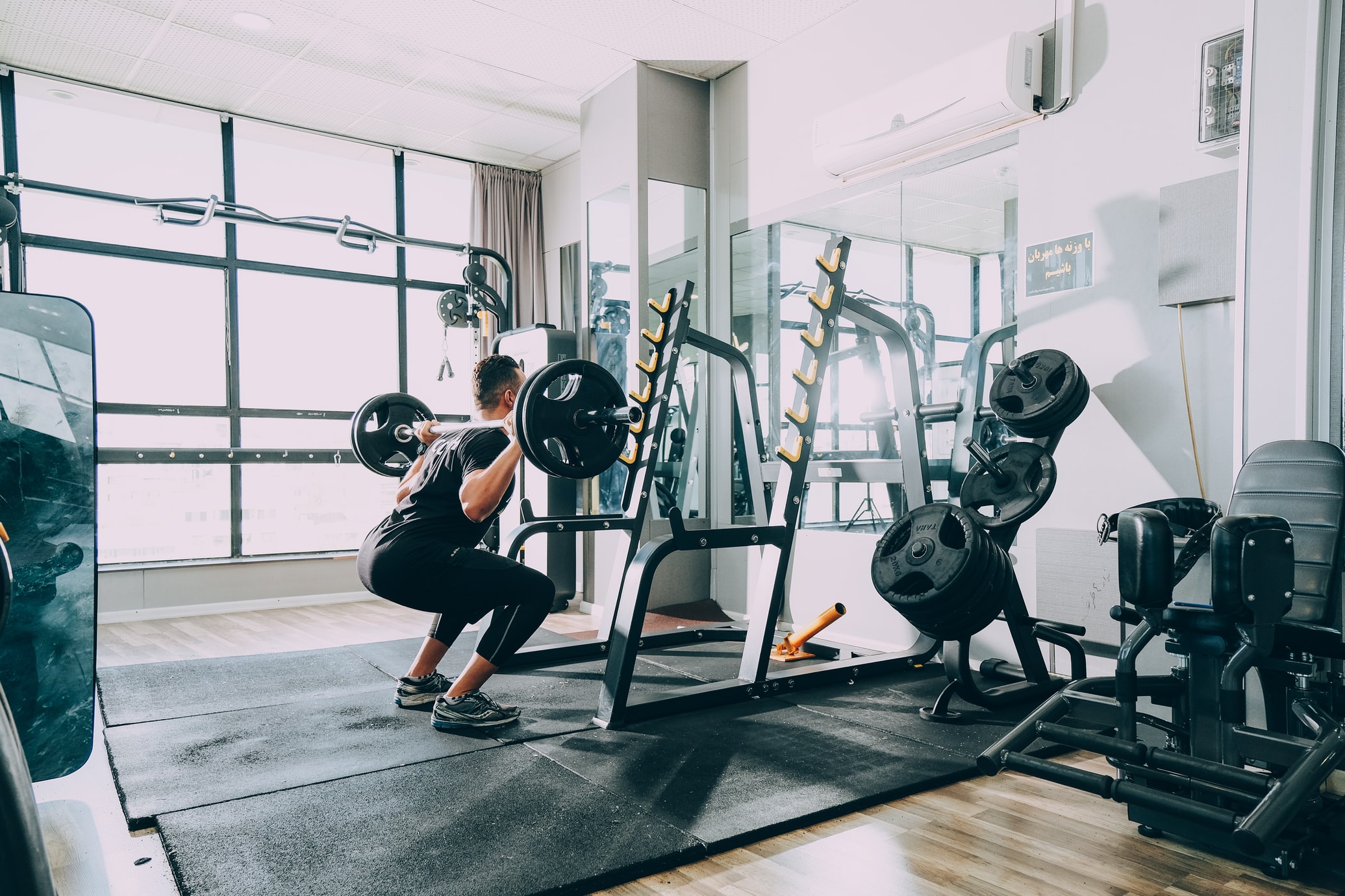 A man does a squatting exercise with weights in the gym