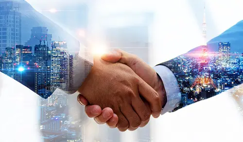 Apretón de manos con una ciudad reflejada de fondo. Alianza estratégica entre Bigle y PwC